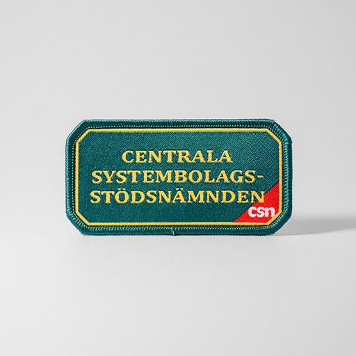 Grönt tygmärke med texten "Centrala Systembolagsstödsnämnden"